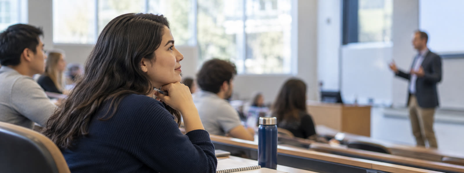 Adult learner listening to an academic talk in a university classroom.